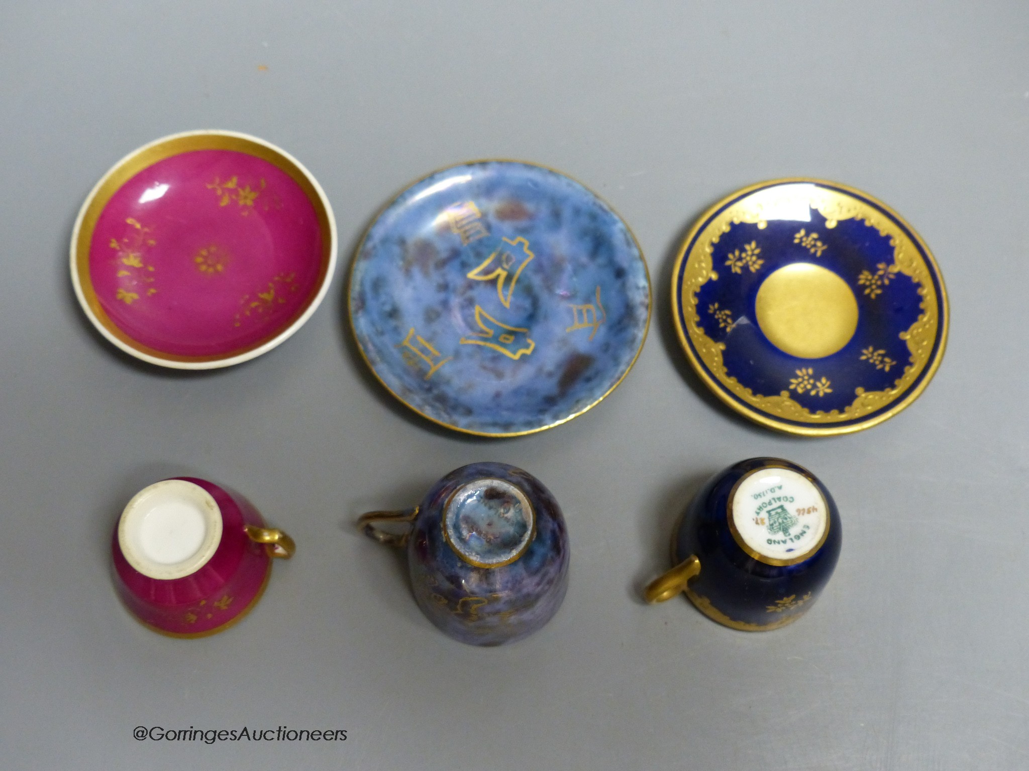 A Wedgwood lustre miniature cup and saucer with gilt decoration, a Coalport blue and raised gilt cup and saucer and a Grainger Worcester claret ground miniature teacup and saucer, tallest 3.5cm including saucer